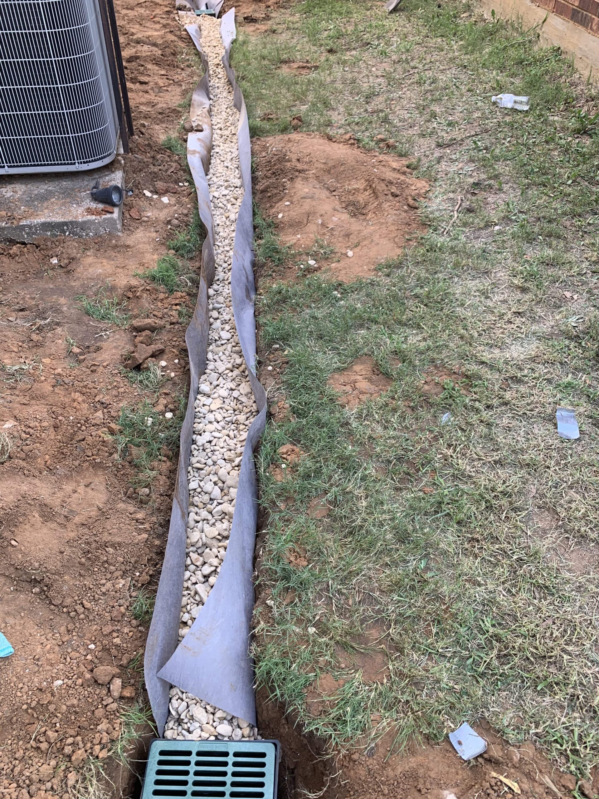 PVC pipe and catch basin being installed for a French drain system.